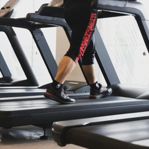 A person walking on a treadmill in a modern gym setting, focusing on fitness.